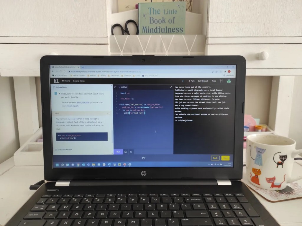 A laptop displaying code, on a restored white writing desk