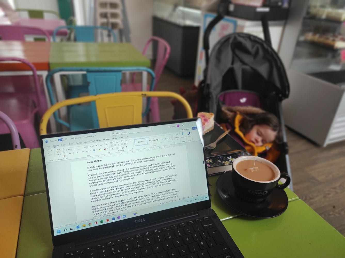 In the cafe, my computer screen displaying my Word document while writing this blog post, with my little daughter asleep in a pushchair in the background.